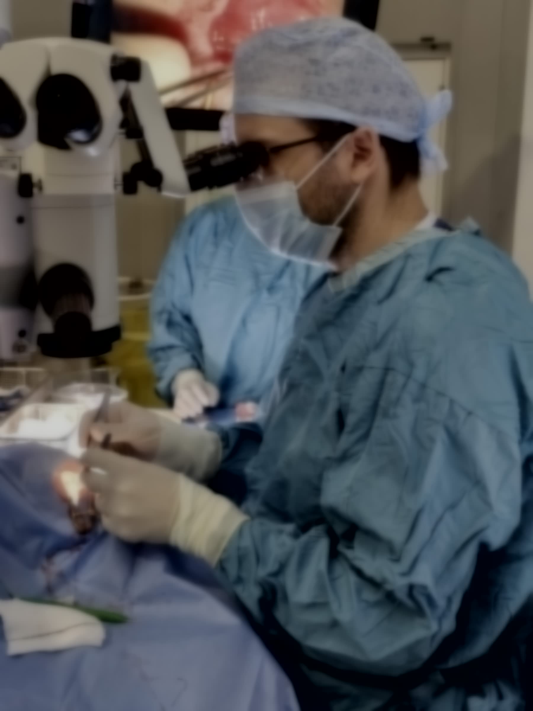 A surgeon operating under a microscope in a sterile operating theatre.